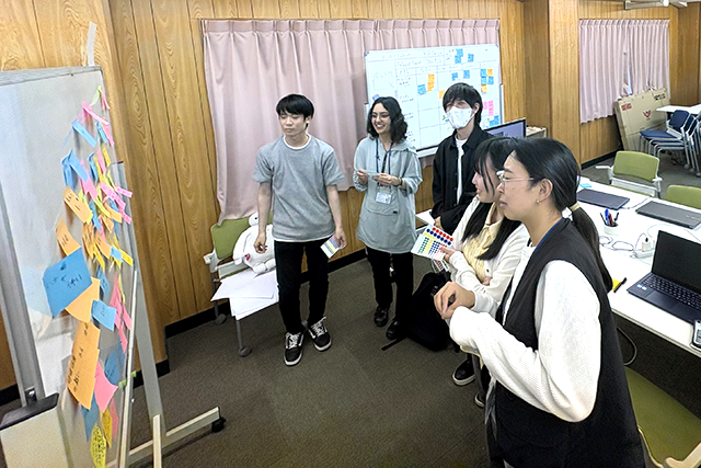 学生たちがホワイトボードに付箋を貼ってアイデアを検討している様子