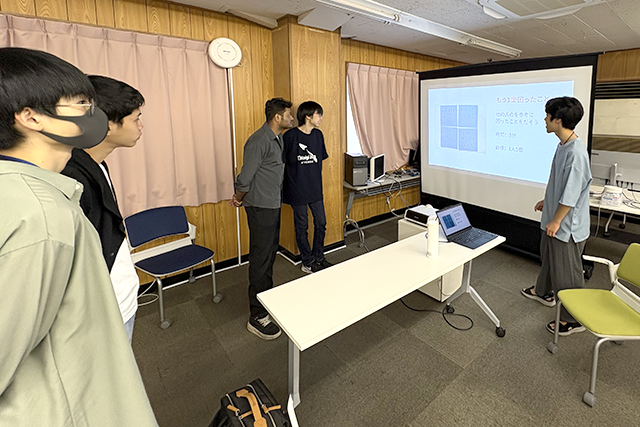 プロジェクターでテーマを表示して、発表をする学生の様子