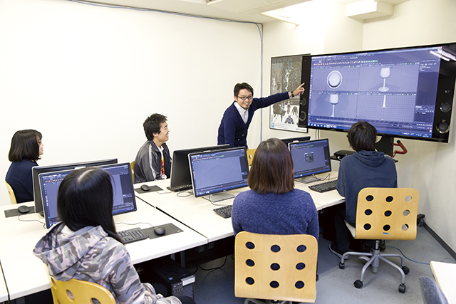 3DCGツールを見せながら、学生に指導する教員の写真