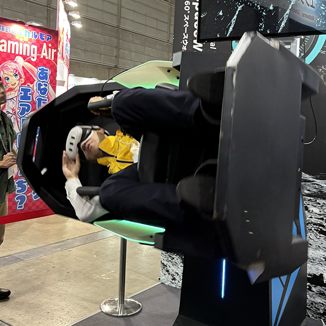 360度回転する椅子とVRゴーグルをつけて試乗する人の写真
